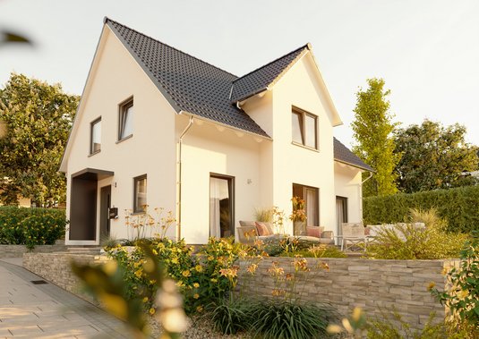 Modernes Massivhaus als Beispiel im Vergleich zum Fertighaus Modernes Massivhaus mit heller Putzfassade und großen Fenstern im Grünen, symbolisch für den Vergleich von Massivhaus und Fertighaus in Bauweise und Qualität