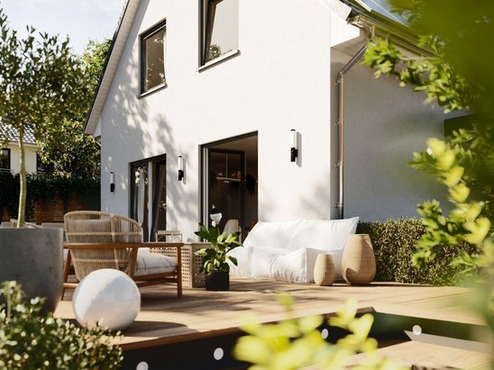 Massivhaus Raumwunder 90 mit heller Fassade und klarer Linienführung, im sonnigen Garten fotografiert, steht für kompakte Bauweise und hohe Energieeffizienz.