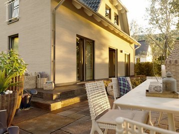 Blick auf die Terrasse eines Massivhauses mit Garten. Beispiel für individuell gestaltbare Außenflächen.