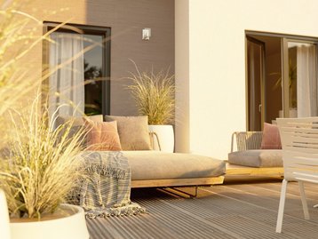 Massivhaus mit Terrasse im Abendlicht. Beispiel für lichtdurchflutetes Wohnen mit Gartenbezug.